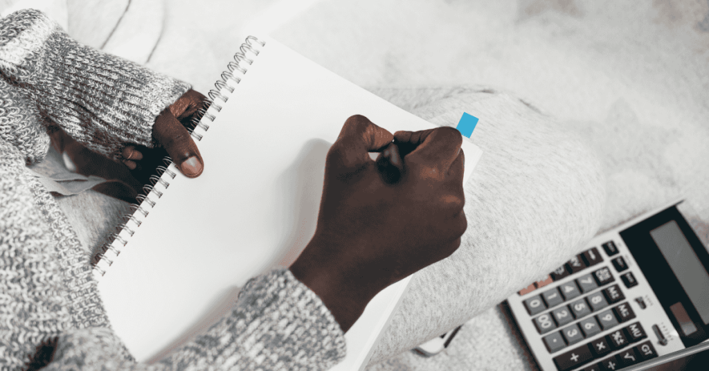 picture of a hand holding a pen writing on a paper. the person is in the process of writing.