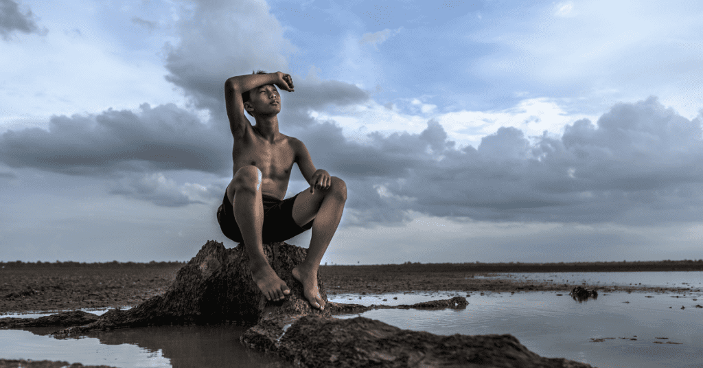 cover photo of a poem by contemporary nigerian poet, Praise Osawaru. In the cover photo, a boy is sitting on a rock across an ocean.